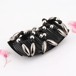Detail of beaded magic hair comb with black and silver beads on a white surface