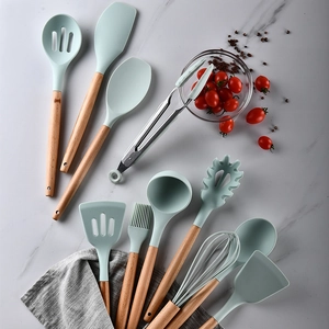 11-piece set of mint green silicone kitchen utensils with wooden handles on marble surface