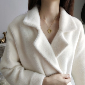 Detailed view of a gold cross heart pendant necklace on soft off-white plush fabric