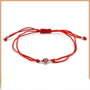 Detailed view of handmade red braided evil eye bracelet with adjustable cord and beads