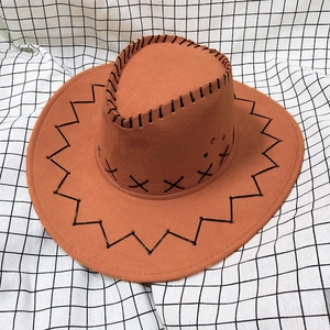 Detail of the brown cowboy hat featuring decorative black cross-stitching on the brim