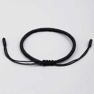 Detail of hand-woven black cord bracelet featuring adjustable knot closure and texture