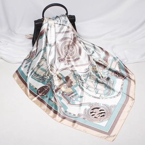 Detail of nautical square silk scarf with anchor and ship prints draped on a black handbag