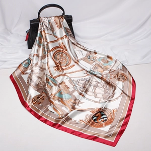 Detail of silk-like square scarf with nautical patterns draped over a black handbag
