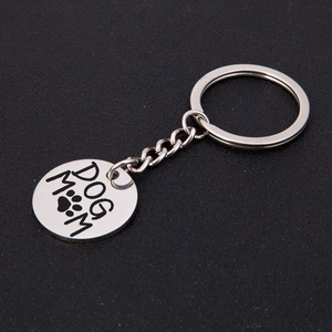 Polished silver stainless steel Dog Mom keychain with paw print on black background