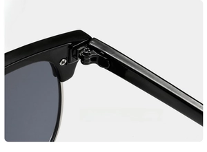 Macro detail of high-gloss black sunglass frame showing the solid metal hinge design