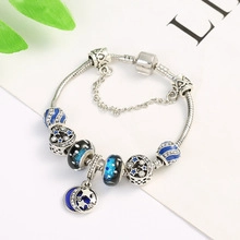 Detail showing silver charm bracelet with blue star beads and moon pendant