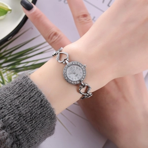 Nahaufnahme der herzförmigen Quarzuhr in Silber mit Strass-Lünette an einem Damenhandgelenk