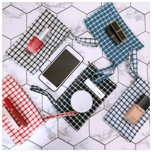 Detailed overhead view of plaid fabric pouches with convenient wrist straps in three colors