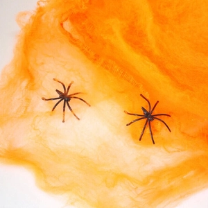 Halloween decorative cobwebs with realistic black plastic spiders on orange cotton mesh
