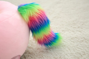 Détail d'un fauteuil licorne en peluche avec une queue colorée en fausse fourrure arc-en-ciel
