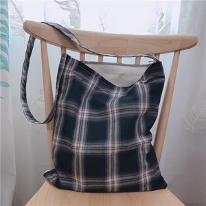Détail d'un sac cabas en toile à carreaux bleus avec large bandoulière sur une chaise