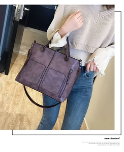 Detail of dark purple faux leather tote with functional front zippers and shoulder straps