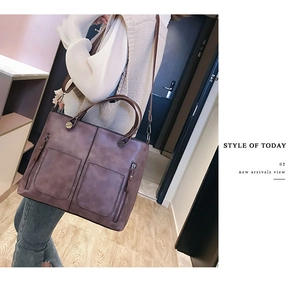 Detail view of large dark purple distressed leather tote bag with dual front zipper pockets