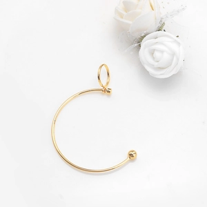 Minimalist golden C-shape metal earring with spherical detail on a white background
