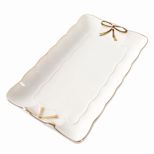 Elegant white ceramic jewelry tray with gold bow handles and trim in minimalist Nordic style