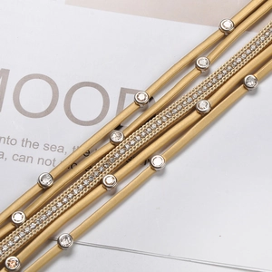 Detailed macro view of multilayered gold leather bracelet with white rhinestones