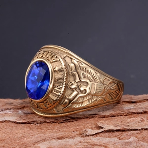 Detail of a gold US Army ring with a blue oval gemstone set against a rustic wood background