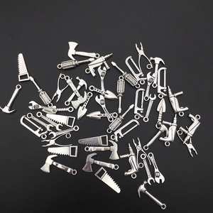 Miniature silver metal tool pendants including hammer and wrench on black background
