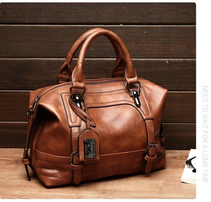 Detail of dark brown leather Boston bag with vintage oil wax finish and metallic hardware