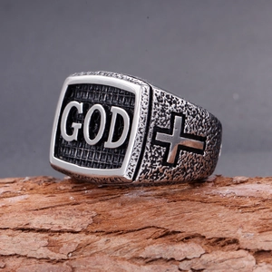 Macro shot of retro GOD ring in stainless steel with cross symbol on rustic wood
