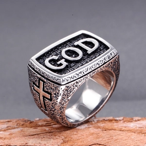 Macro detail of vintage stainless steel GOD ring with cross engraving on wood block