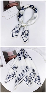 Detailed view of floral silk scarf featuring elegant blue roses on off-white satin fabric