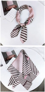 Detail of pink and black striped silk scarf styled with modern decorative accessories