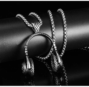 Macro view of silver headphone pendant with textured ear cups on a box chain necklace