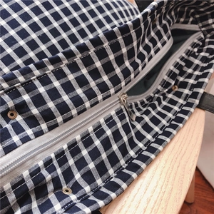 Close-up of fine check pattern cotton fabric with silver zipper and metal eyelet detail
