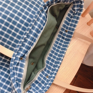 Detail view of blue checkered tote bag with secure zipper and durable green lining