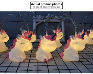 Detail of warm glow LED unicorn string lights with soft purple hair on checkered fabric