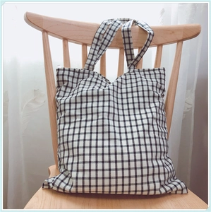 Sac fourre-tout en toile à carreaux noir et blanc suspendu à une chaise en bois