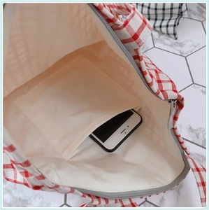 Vue intérieure du sac en toile à carreaux rouges avec poche pratique pour un smartphone
