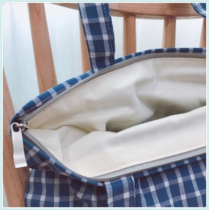 Détail du sac cabas à carreaux bleus montrant la fermeture zippée et la doublure beige