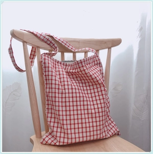 Détail du sac cabas en coton à carreaux rouges et blancs sur une chaise en bois