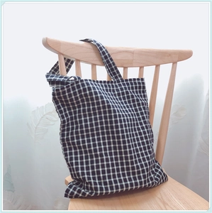 Détail d'un sac en toile à carreaux avec double poignée suspendu à une chaise