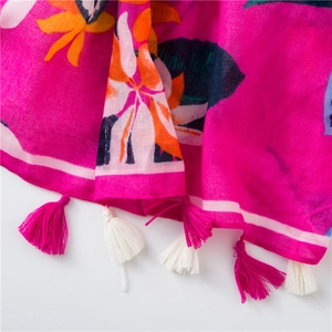 Detailed close-up of tropical floral print on a fuchsia scarf with colorful fringe edges