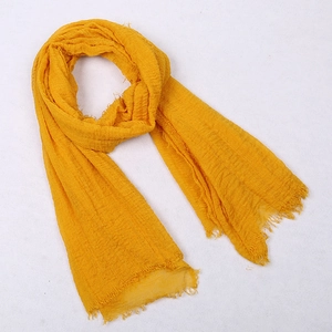 Solid yellow voile scarf with crinkled texture and fringed edges on white background