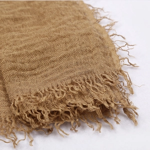 Brown cotton linen voile scarf with fringe tassels and pleated texture on white background