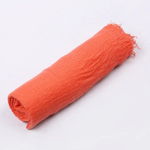 Detail view of coral orange crinkle cotton scarf showing soft texture and frayed edges