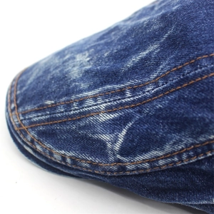 Detailed close-up of dark blue denim cap brim featuring orange stitching and washed texture