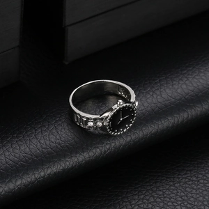 Macro shot of silver watch-shaped ring with black dial and white crystal accents