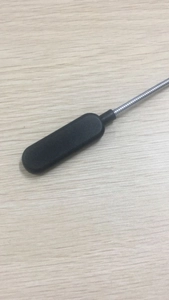 Close-up of flexible metal gooseneck with black LED lamp head on a wooden table