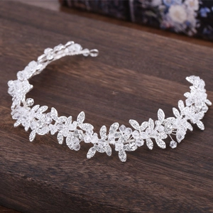 Dettaglio del cerchietto da sposa floreale argento con cristalli su fondo di legno