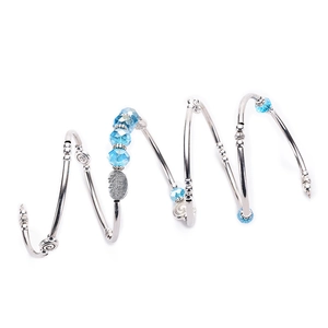 Spiral silver bracelet with blue crystal beads and engraved leaf charm on white background