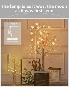 Close-up of LED birch tree lamps with warm white lights and spherical glass ornaments