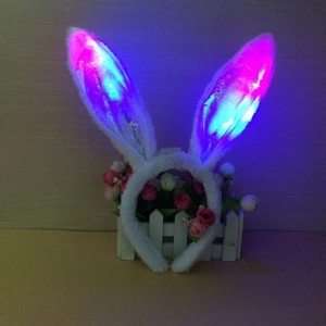 Detailed close-up of white plush LED rabbit ears headband glowing in pink and blue light