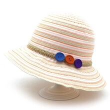 Detail of colorful striped paper straw hat with vibrant decorative side buttons