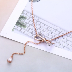 Macro detail of rose gold bow necklace with sparkling zircon fringe and teardrop pendant